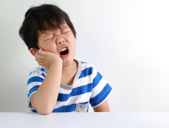 Assottigliamento dello smalto in estate: bambino con fitta ai denti per sensibilità dentale