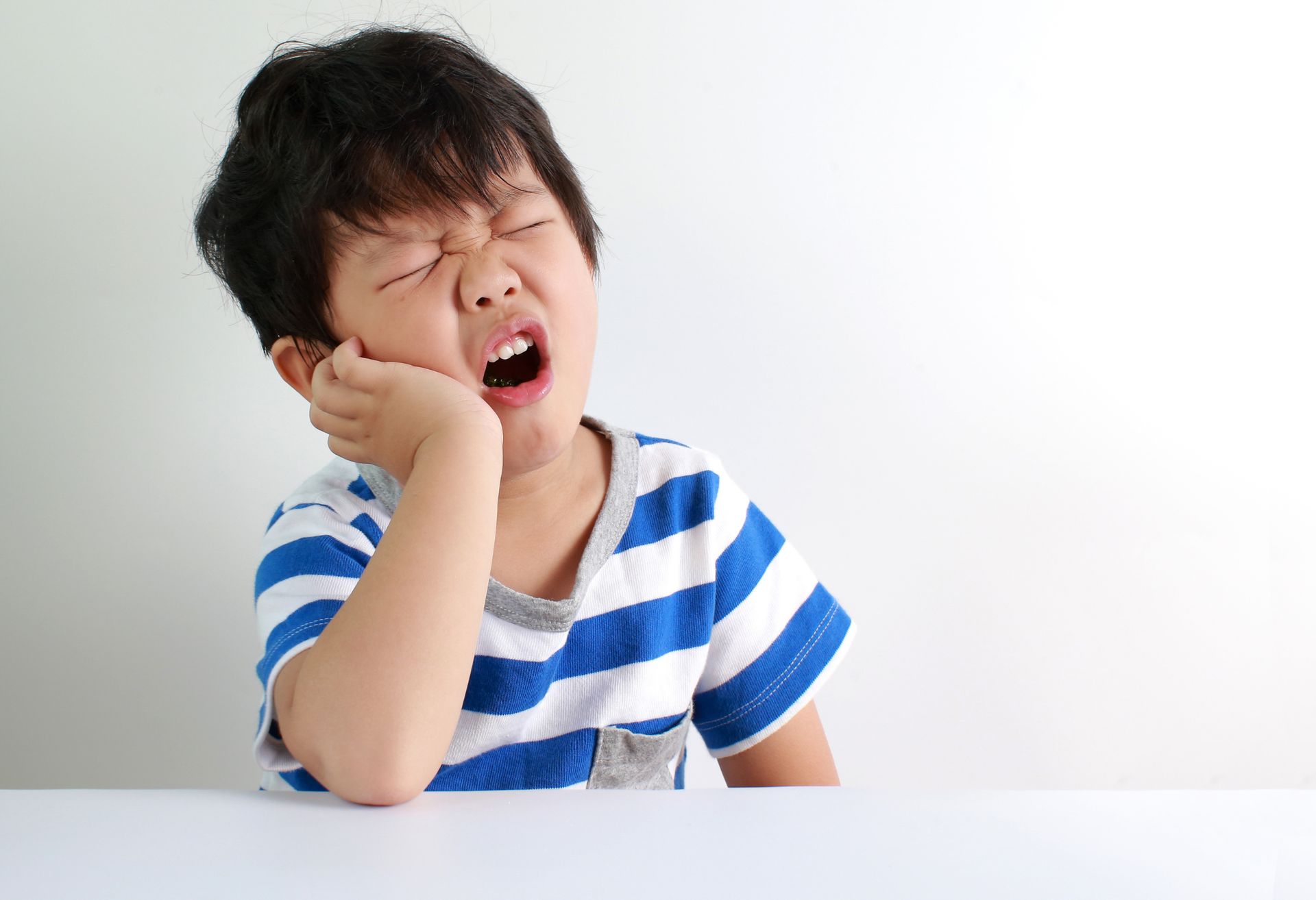 Assottigliamento dello smalto in estate: bambino con fitta ai denti per sensibilità dentale