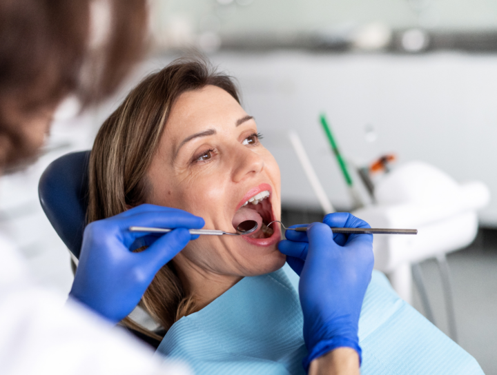 Afte ricorrenti: dentista che esamina la bocca di una paziente durante una visita di controllo
