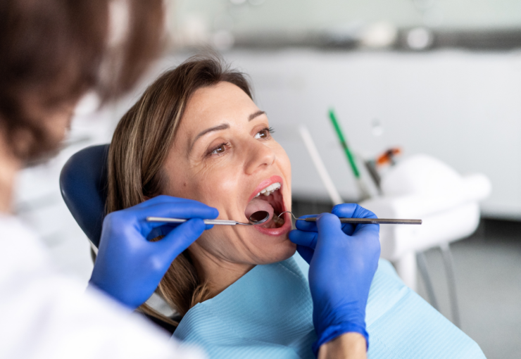 Afte ricorrenti: dentista che esamina la bocca di una paziente durante una visita di controllo