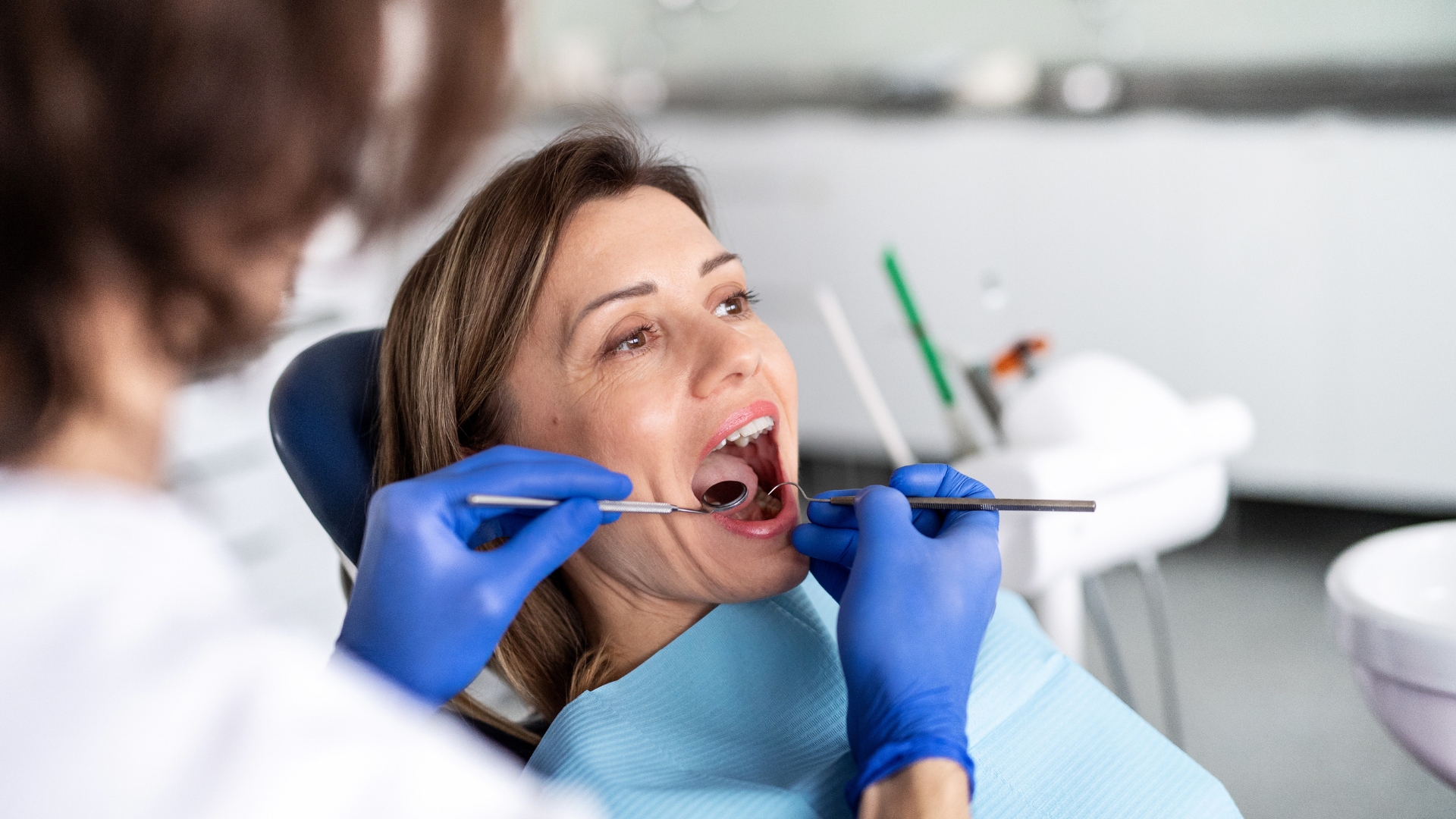Afte ricorrenti: dentista che esamina la bocca di una paziente durante una visita di controllo