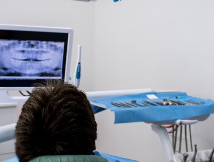 Radiografie dentali: paziente in poltrona osserva una radiografia panoramica su uno schermo in studio