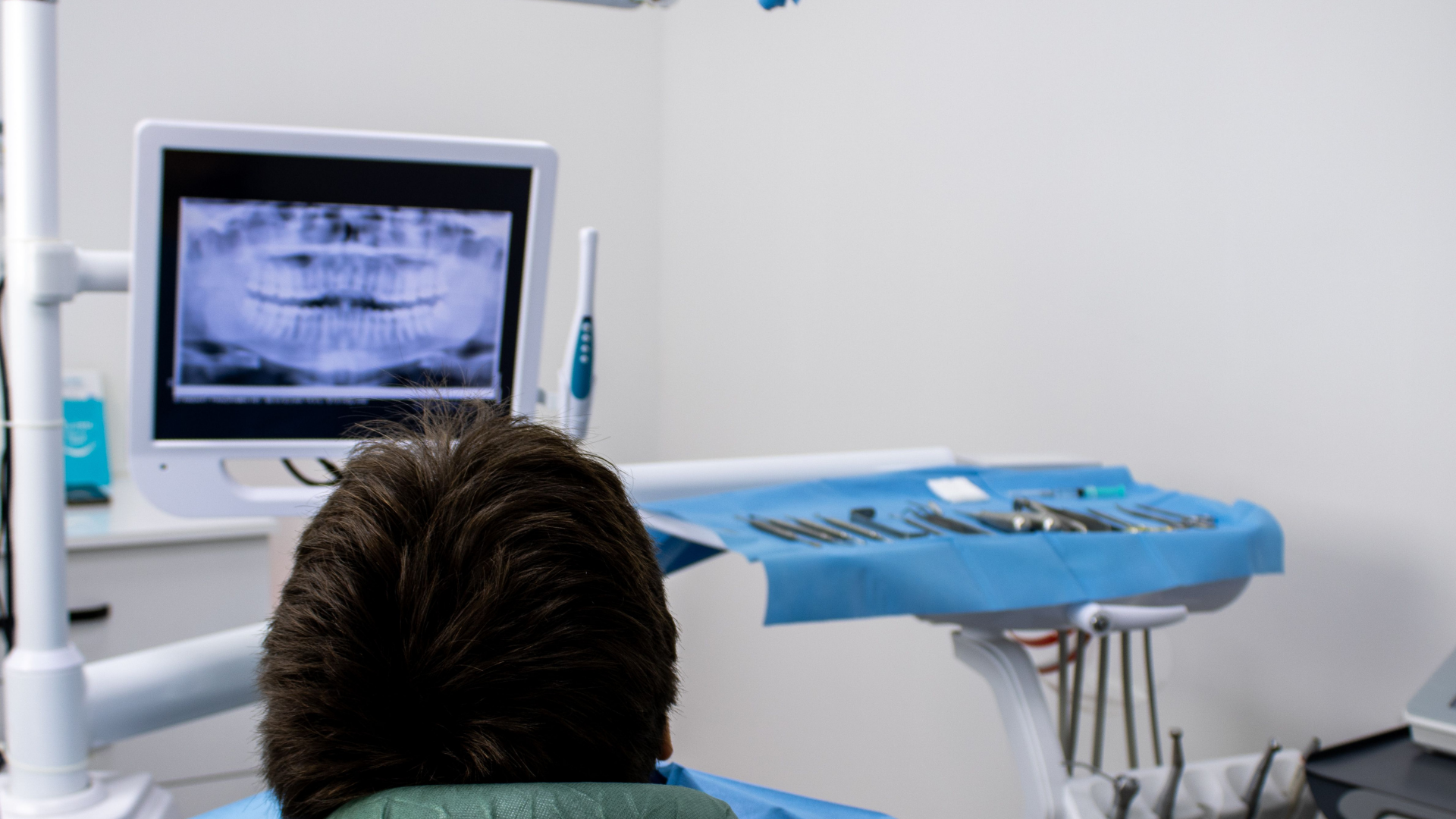 Radiografie dentali: paziente in poltrona osserva una radiografia panoramica su uno schermo in studio